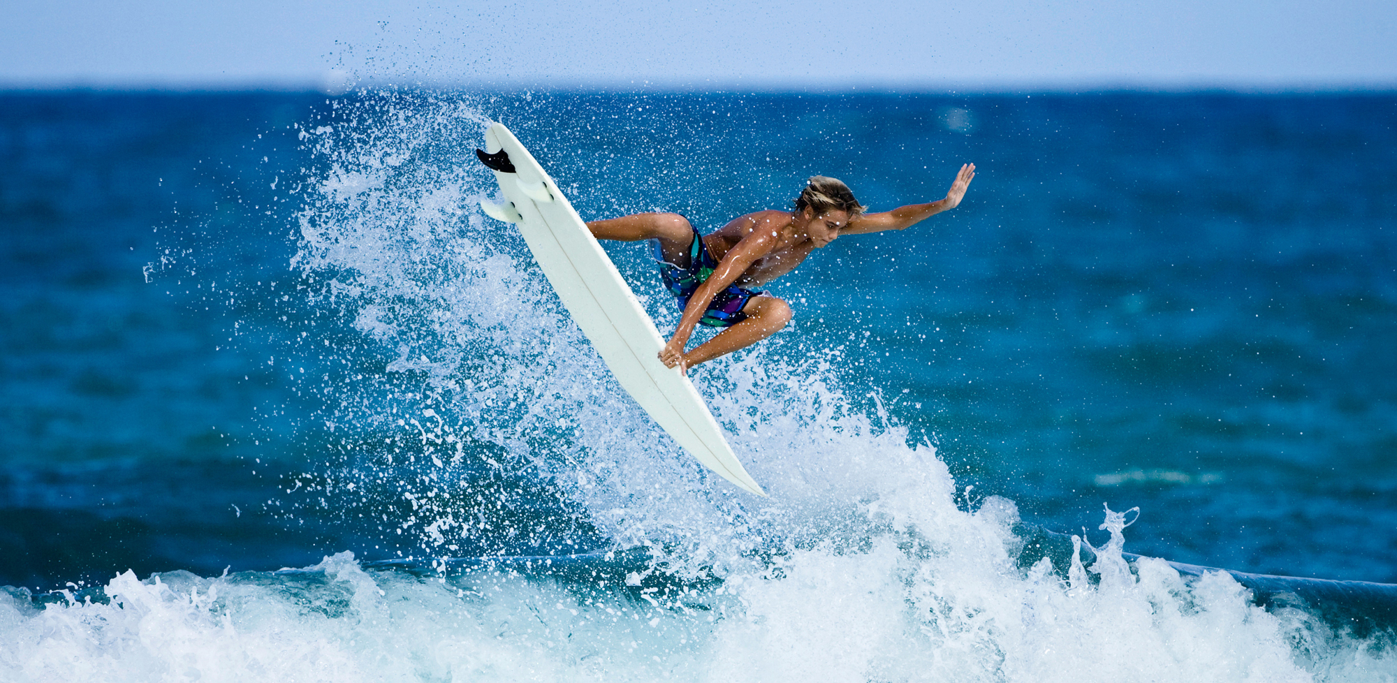 A person surfing wearing Mack's Earplugs