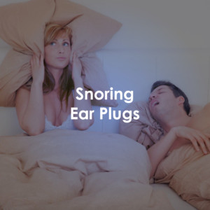 A woman in bed with her partner. She is covering her ears with a pillow. Her partner is snoring. Text on top the image reads, "Snoring Earplugs".