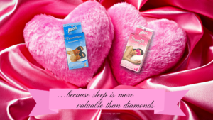 Dreamgirl and Dreamweaver Sleep Mask packages from Mack's earplugs sitting on two fluffy heart pillows for Valentine's day